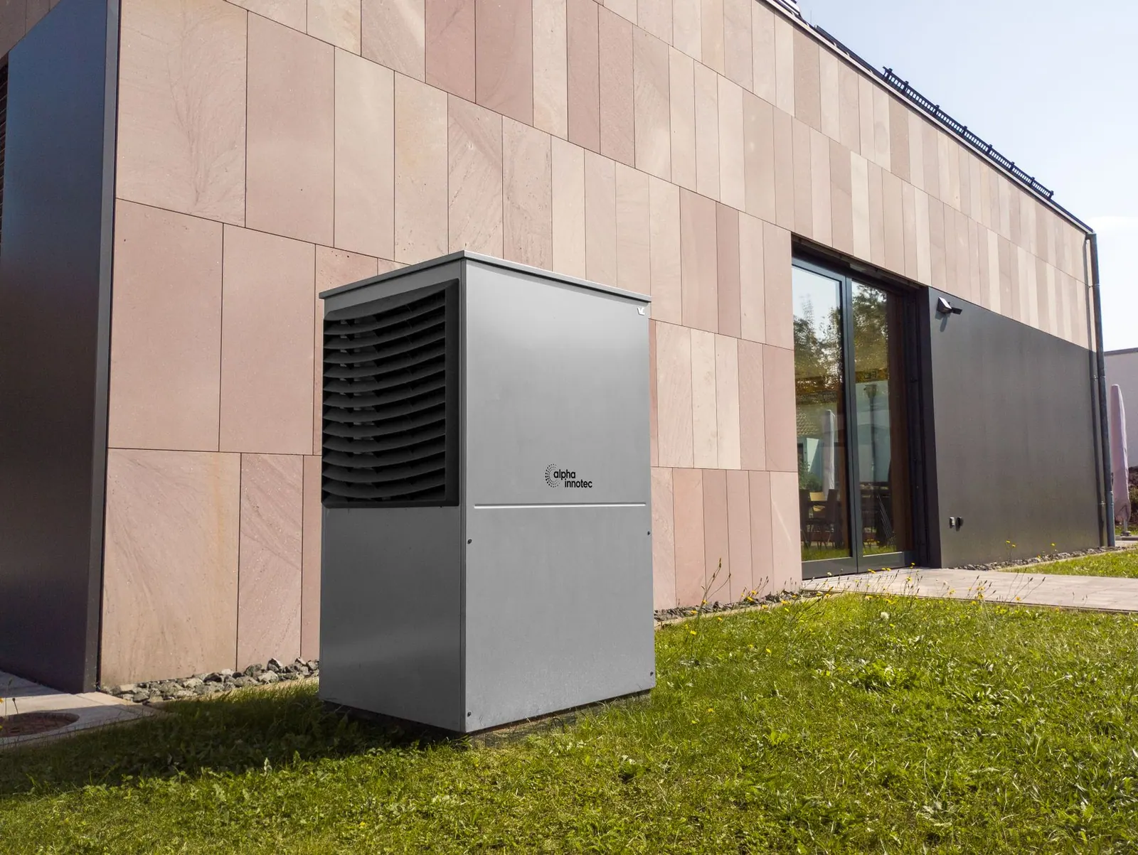 A modern heat pump unit installed outdoors next to a contemporary building, showcasing renewable energy technology. BC Hydro and FortisBC heat pump rebates: how they stack in 2025