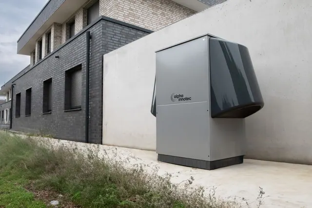 Innovative heat pump system by alpha innotec installed outside a contemporary building. Heat pump water heater vs. gas tankless: a cost and performance comparison